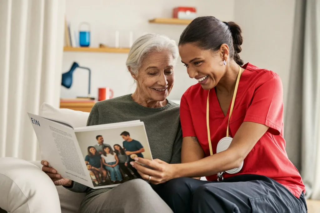 A caregiver and a senior woman looking through a family photo album together