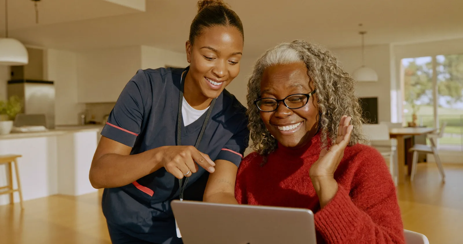 A caregiver helping a senior woman video-call her family on a tablet