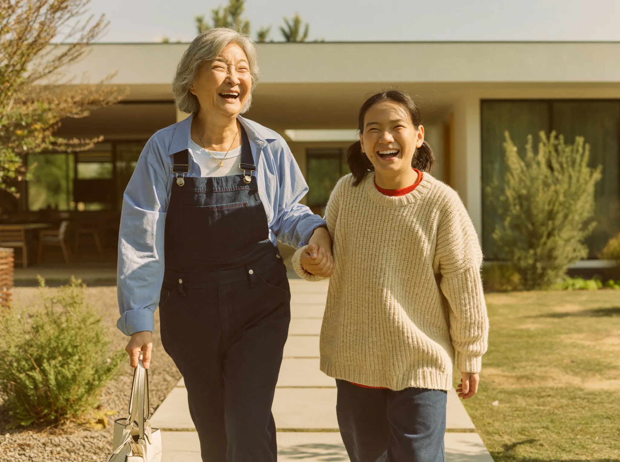 A senior woman and a younger companion walking arm in arm through a sunlit garden