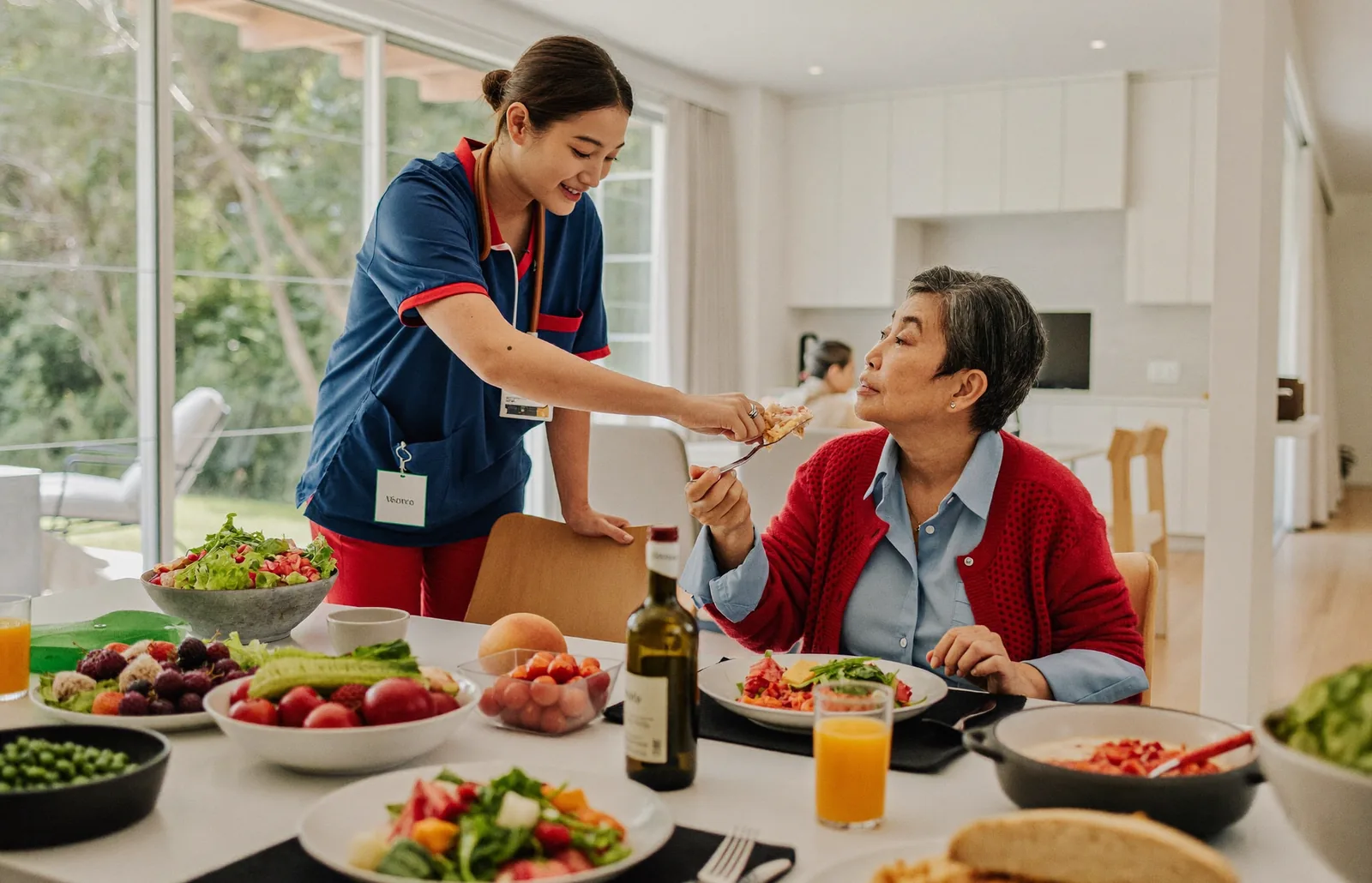 A caregiver and a senior enjoying a healthy meal together at a sunlit dining table